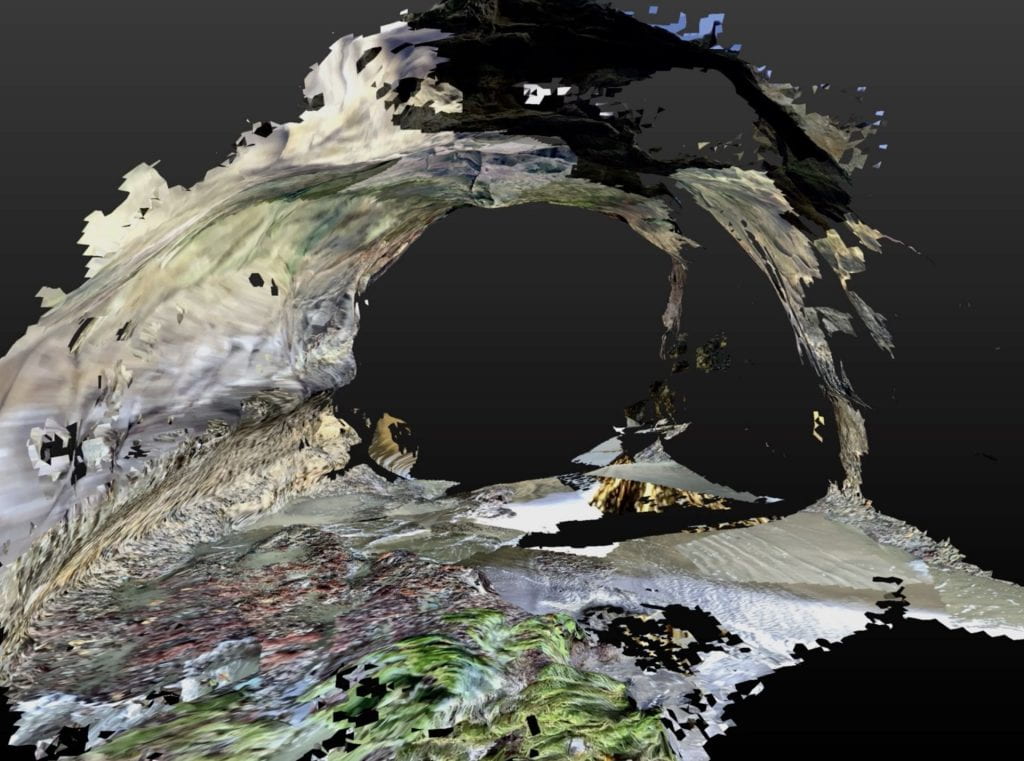 Glitchy 3-D scan of a rock bridge with moss and waves